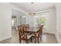 Bright dining room with wood floors, a chandelier, and a window with white curtains for natural light at 9251 Palm Bay Cir, Raleigh, NC 27617