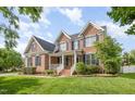 Charming two-story brick home with a well-manicured lawn and inviting front porch with white railing at 9251 Palm Bay Cir, Raleigh, NC 27617