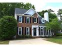 Charming two-story brick home with black shutters, manicured landscaping, and a paved driveway at 103 Romaine Ct, Cary, NC 27513