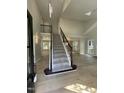 Bright foyer with high ceilings, wood floors, and carpeted stairs with dark wood and wrought iron railing at 103 Romaine Ct, Cary, NC 27513