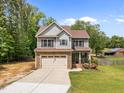 Charming two-story home with stone accents, gray siding, and a well-manicured lawn and long driveway at 104 Anderson Park Dr, Wake Forest, NC 27596