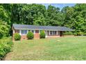 Charming single-story brick home featuring a well-manicured lawn and mature trees at 1041 Davis Dr, Apex, NC 27523