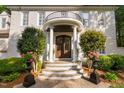 Close up on grand front entrance with double doors, pillars and manicured shrubs with potted pink flowers at 106 Clendenen Ct, Cary, NC 27513