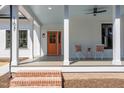 Inviting front porch with stylish seating, a painted ceiling and an orange front door at 107 N Guthrie Ave, Durham, NC 27703