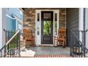 Inviting front porch with rocking chairs, stone accents, and black trimmed entry door at 1209 Harp St, Raleigh, NC 27604