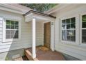 Inviting front porch with classic wooden door, flanked by bright, sunlit windows, creating a warm welcome at 1316 Glenwood Ave, Raleigh, NC 27605