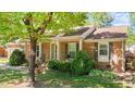 Side view of the brick home highlighting the covered porch, windows with shutters, and landscaping at 1612 Regency Dr, Burlington, NC 27215