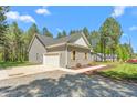 Side view of a single-story gray home, showcasing the driveway and an attached garage, surrounded by mature trees at 1840 Willie Pace Rd, Burlington, NC 27217