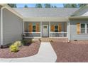 Inviting front porch with white railing, brick base, and stylish front door, complemented by well-maintained landscaping at 1840 Willie Pace Rd, Burlington, NC 27217