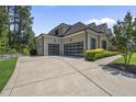 Spacious three-car garage with modern glass doors and a paved driveway, surrounded by manicured bushes at 209 Preston Retreat Ln, Cary, NC 27513