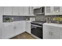Close up of kitchen featuring stainless appliances, white cabinets, and designer backsplash at 25 Westbourne Ln, Youngsville, NC 27596