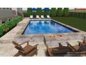 Backyard pool featuring an outdoor fireplace, Adirondack chairs, lounge chairs, and manicured landscaping at 25 Westbourne Ln, Youngsville, NC 27596