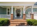 Welcoming porch with brick accents leads to a charming home with a beautifully adorned front door at 304 Nelson Ln, Clayton, NC 27527
