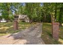 A long driveway leading up to a two-story house surrounded by lush greenery and mature trees at 3113 Chelmshire Ct, Raleigh, NC 27610