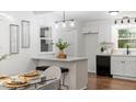Modern kitchen with white cabinets, black appliances, and bar seating at 3907 Inwood Dr, Durham, NC 27705