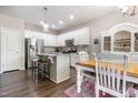 Bright kitchen featuring white cabinets, stainless steel appliances, a granite island, and a dining area with wood floors at 420 Cherry St, Fuquay Varina, NC 27526
