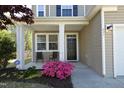 Inviting front porch featuring a black door, seating and lovely flowering shrubbery at 621 Childsberg Way, Hillsborough, NC 27278