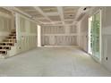 Unfinished living room with stairway, drywall and door to the outside at 629 Conover Rd, Durham, NC 27703