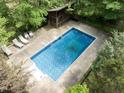 This backyard swimming pool includes lounge chairs, decking, and wooded views at 1000 Phils Creek Rd, Chapel Hill, NC 27516