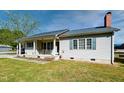 Charming single-story home featuring a covered front porch, light siding and green shutters at 107 N Pearl St, Princeton, NC 27569