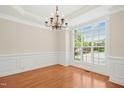Bright dining room features hardwood floors, large window, elegant chandelier, and classic wainscoting at 1103 Weston Green Loop, Cary, NC 27513