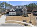 Striking two-story home featuring a mix of white board and batten siding and brick with dark shutters at 113 Amberwing Ct, Holly Springs, NC 27540