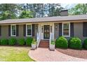 Inviting front entrance with a brick walkway, decorative plants, and a classic dark-stained door at 1305 Kimberly Dr, Raleigh, NC 27609