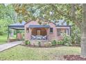 Charming brick house with mature landscaping, featuring a quaint front porch and inviting curb appeal at 1307 Arnette Ave, Durham, NC 27707