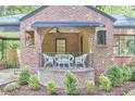 Inviting front porch with brick accents, offering a cozy seating area for relaxing outdoors at 1307 Arnette Ave, Durham, NC 27707