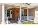 Inviting front porch with white columns, brick accents, and a cozy seating area perfect for relaxing outdoors at 1437 Chelton Oaks Pl, Raleigh, NC 27614