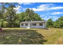 Charming white home featuring a brick facade, decorative shutters, manicured landscaping, and inviting front porch at 1732 Green Pace Rd, Zebulon, NC 27597