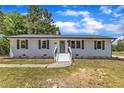 Charming white home featuring a brick facade, decorative shutters, manicured landscaping, and inviting front porch at 1732 Green Pace Rd, Zebulon, NC 27597