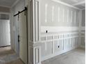 View of a room under construction with board and batten wall accents and a sliding barn door at 196 Cozy Brook Ct, Clayton, NC 27520