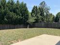 Fenced backyard with mature trees surrounding the perimeter and a concrete patio area at 2018 Groundwater Pl, Raleigh, NC 27610