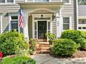 Inviting front porch with brick steps, lush greenery, and an American flag, adding charm to the home's entrance at 204 Rossburn Way, Chapel Hill, NC 27516