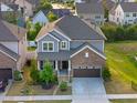 An aerial view of a gray two-story home with stone accents, complemented by a well-manicured lawn at 232 Kanewind Ter, Apex, NC 27523