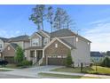 A two-story gray home with stone accents, a two-car garage, and mature landscaping at 232 Kanewind Ter, Apex, NC 27523