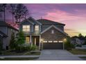 Beautiful two-story home with stone accents and gray siding, illuminated by a stunning sunset at 232 Kanewind Ter, Apex, NC 27523