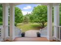 Covered porch view of green lawn with mature trees and landscaping at 303 Crooked Meadow Ln, Hillsborough, NC 27278