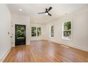 Open living room with white walls, hardwood floors, large windows and a stylish ceiling fan at 310 W Club Blvd, Durham, NC 27704