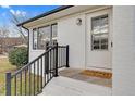 Inviting front porch with a welcoming doormat, black railings, white painted brick, and natural light at 311 Nc 56, Louisburg, NC 27549