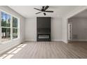 Bright living room featuring a large window, modern black fireplace, and wood-look floors at 380 Pilot Ridge Rd, Zebulon, NC 27597