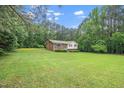 A charming home with a brick facade sits nestled in a lush green lawn, surrounded by towering trees at 4006 Daniel Rd, Durham, NC 27703