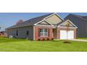 Side view of brick home featuring a well-manicured lawn and attached garage at 493 Lochalsh Dr, Gibsonville, NC 27249