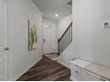 Inviting entryway featuring wood-look floors, staircase, and convenient storage bench at 5054 Kota St, Raleigh, NC 27610