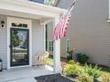 Inviting front porch with decorative chair, well-maintained landscaping, and American flag at 555 Whitley Ridge Dr, Clayton, NC 27527