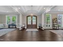 Grand foyer boasts dark hardwood floors, a tray ceiling, and a stylish chandelier, flanked by two sitting areas at 7304 Hasentree Club Dr, Wake Forest, NC 27587