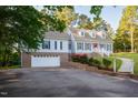 Traditional two story home with two car garage, dormer windows, lush landscaping, and mature trees at 7405 Chickadee Ct, Sanford, NC 27332