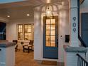 Close-up of a stylish blue front door with glass panels, a welcome mat, and white brick pillars on a cozy front porch at 909 N Gregson St, Durham, NC 27701