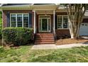 Close-up of a brick home's front entrance with well-maintained landscaping and a welcoming porch at 104 Crossway Ln, Holly Springs, NC 27540